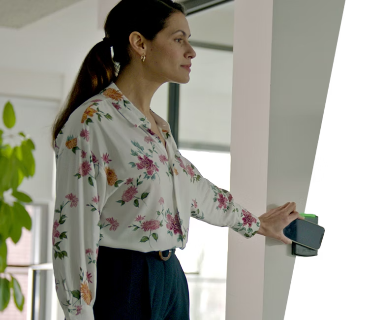 A professional using Alarm.com’s smart access control system to unlock a secure business entrance with a mobile credential for seamless entry.