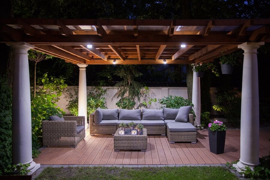 A backyard entertainment setup featuring outdoor lighting and seating under a terrace.