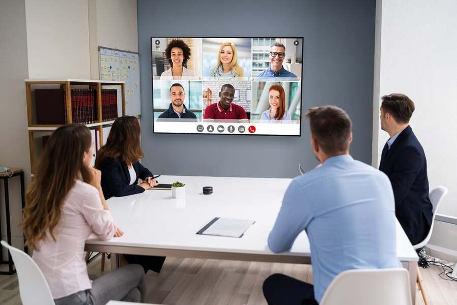 A group of people has a meeting with a hybrid team in a conference room.