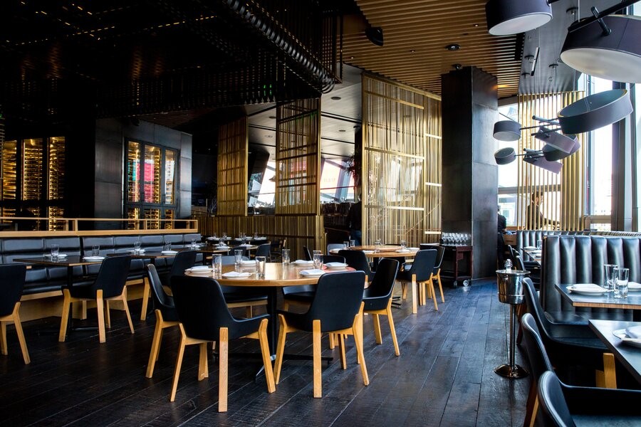 An empty restaurant with hanging pots and dishes as decor.