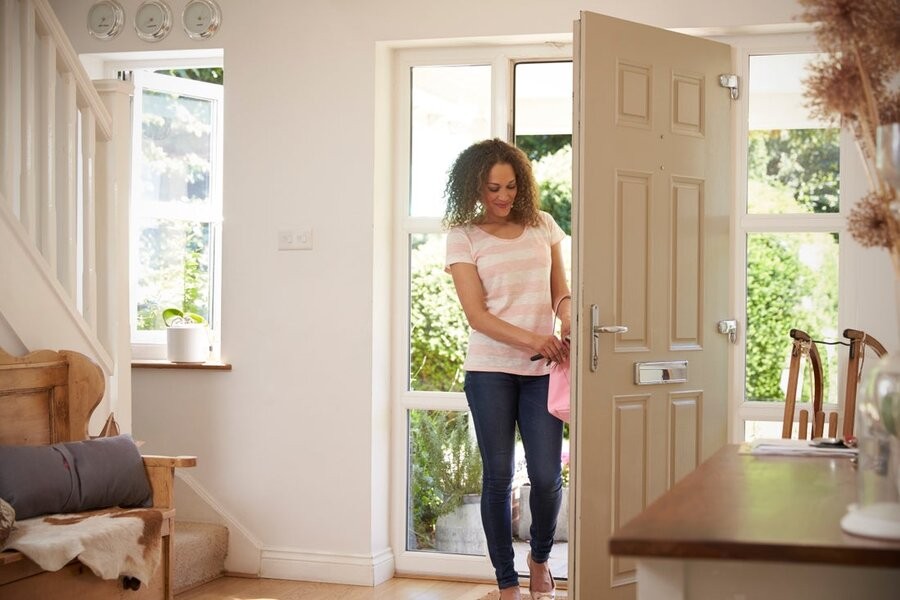 A woman entering her home through the main doorway.