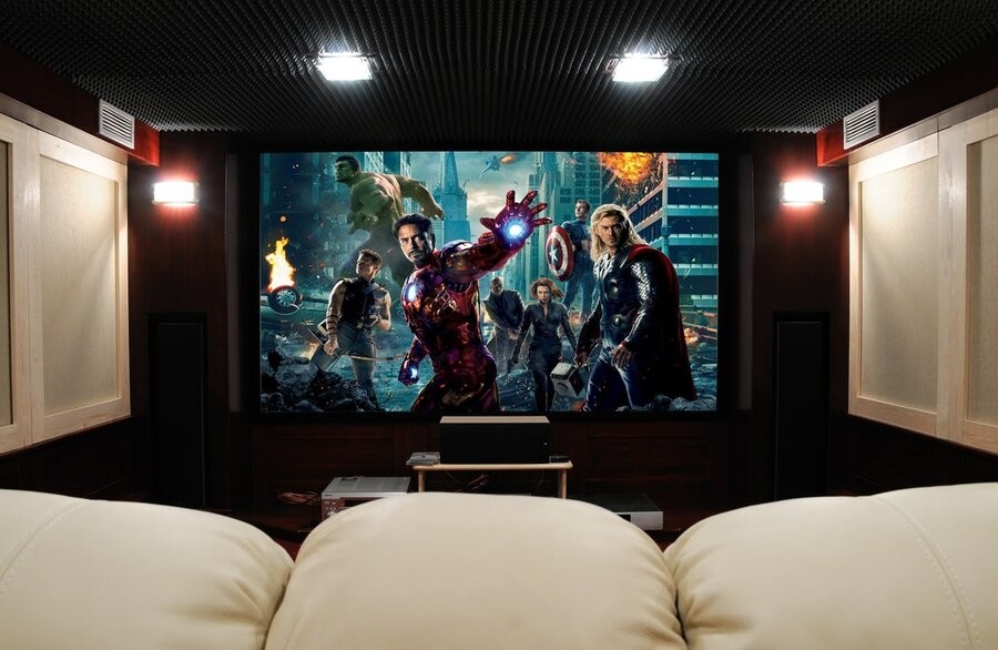 A home theater setup with comfy seating, acoustic paneling, and a large screen displaying The Avengers (2012)