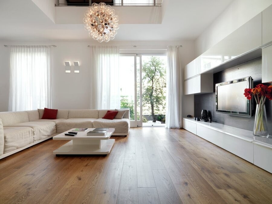 An open living space featuring a media setup, overhead lighting fixtures, and window treatments.