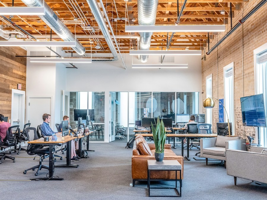 open-concept workplace with people working at computers that overlook large windows