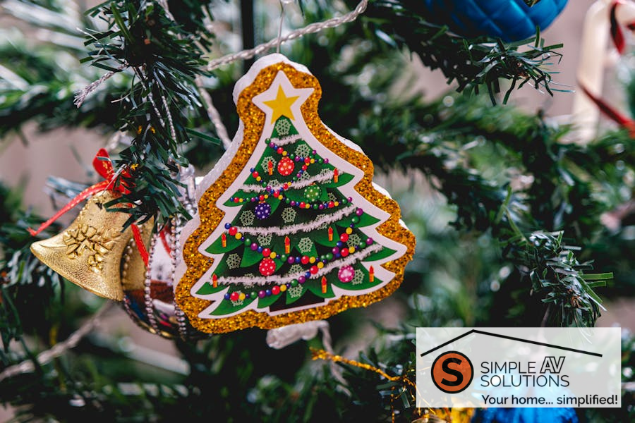 Close-up of a Christmas tree ornament on a decorated tree adorned with glitter and colorful decorations with the Simple AV Solutions logo in the corner.