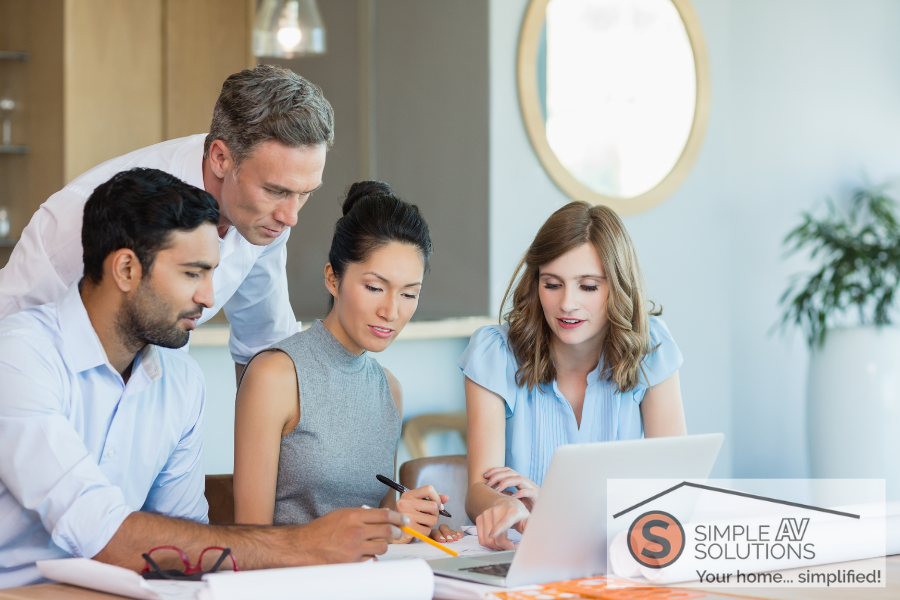 A group of people overseeing content on a laptop with the Simple AV Solutions logo in the bottom right corner.