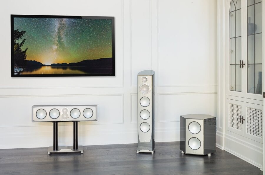 An entertainment space featuring a TV on the wall and several high-end speakers from Paradigm.