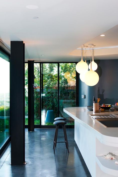 A modern kitchen with large windows, sleek countertops, and contemporary lighting, providing a bright and inviting cooking space.