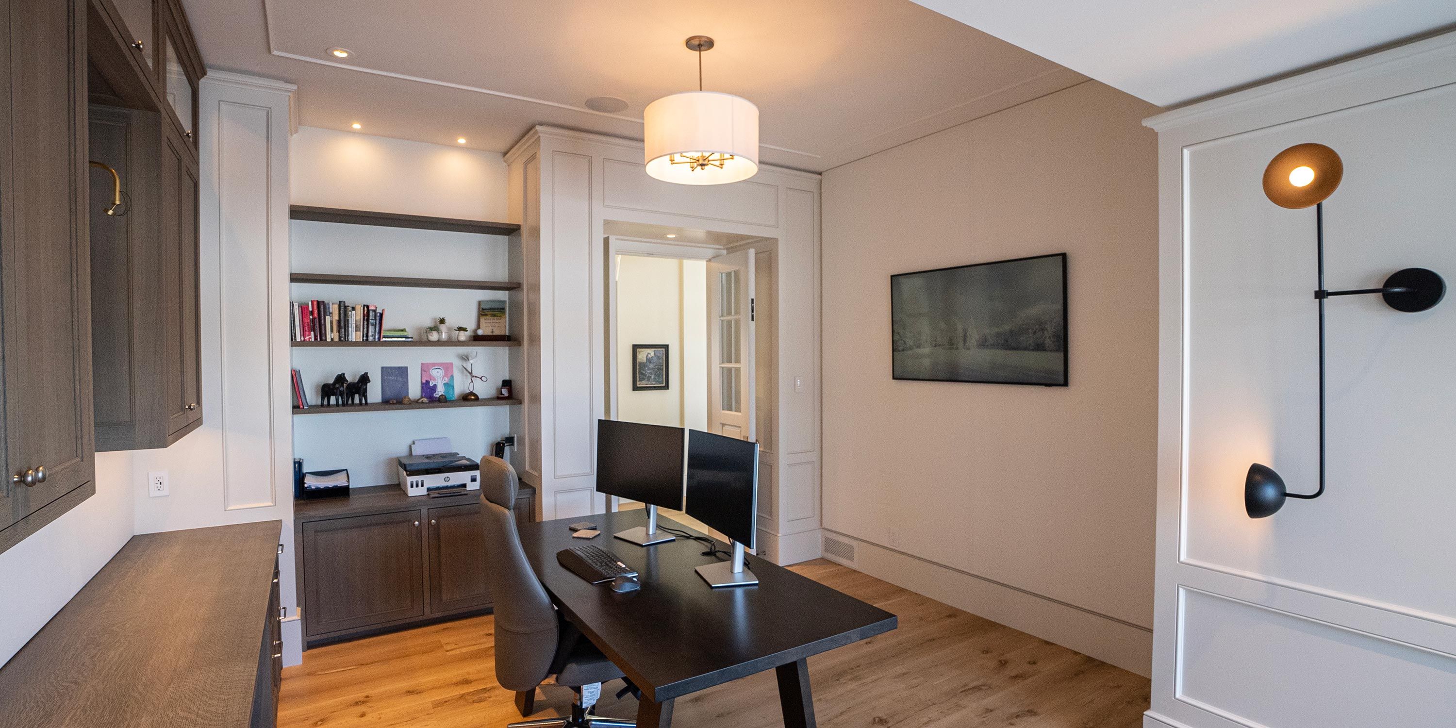 A modern home office with built-in cabinetry, a dual monitor setup, and elegant decor, ideal for focused work in a stylish environment.