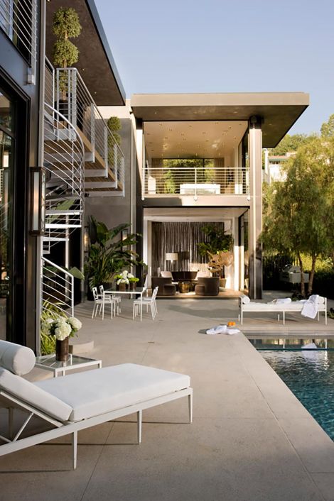 A luxurious outdoor living space with a pool, lounge chairs, and modern architecture, perfect for relaxation and entertaining.