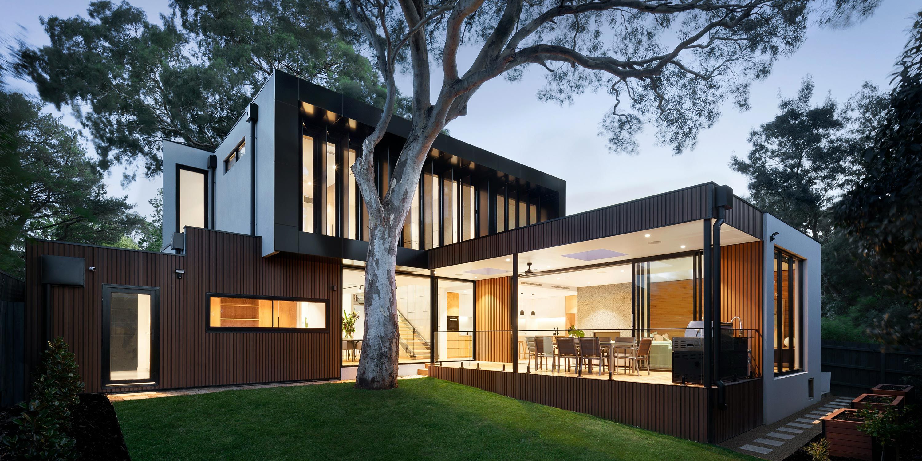 A contemporary home with expansive glass walls and integrated outdoor lighting, blending modern architecture with natural surroundings.