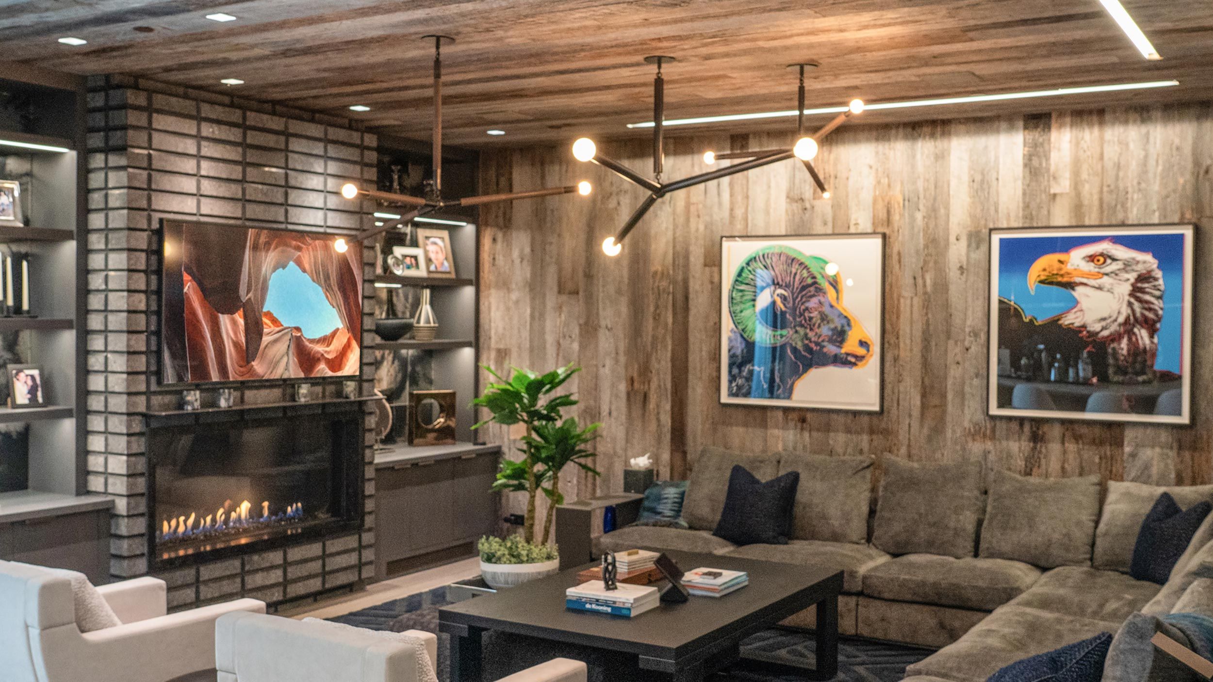 A cozy living room with a large sectional sofa, modern artwork, and a fireplace, designed for a stylish and comfortable entertainment experience.